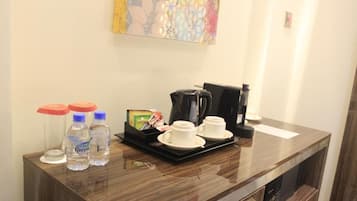 Una recepción de hotel con una cafetera, dos tazas y agua embotellada.
