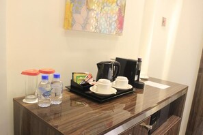 Una recepción de hotel con una cafetera, dos tazas y agua embotellada.