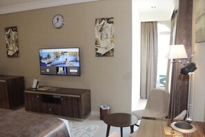 A hotel room with a bed, a TV mounted on the wall, a desk with a lamp, and artwork on the walls. - Tio Sea Resort Al Khor (Al Khor)