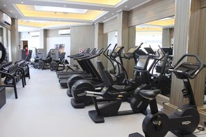 Un gimnasio con cintas de correr, bicicletas estáticas y máquinas de pesas.
