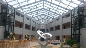 A spacious atrium with a central sculpture, a glass ceiling, and a seating area with a sofa and chairs. - Tio Sea Resort Al Khor (Al Khor)