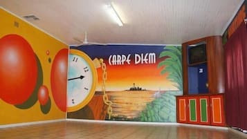 Experience the vibrant mural featuring a clock and cityscape, surrounded by abstract shapes and the inspiring phrase 'CARPE DIEM'.