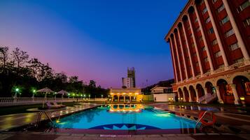 Relax by the pool surrounded by a classical building, featuring a diving area and lounge seating.