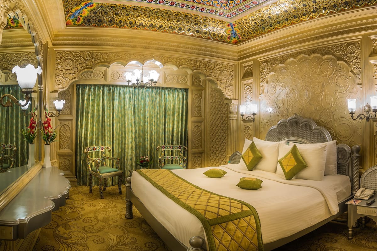 A luxurious room with a large bed, ornate wall decorations, and a chandelier.