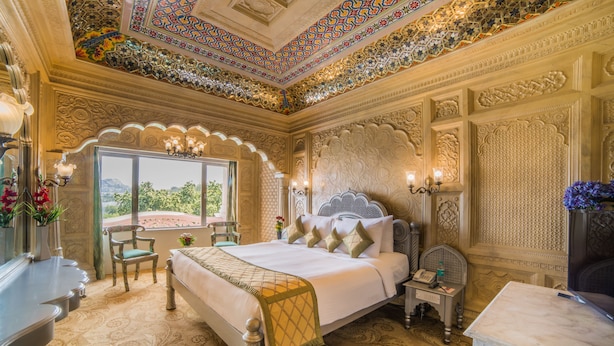 Un dormitorio lujoso con una cama grande, techo decorado y vistas al exterior.