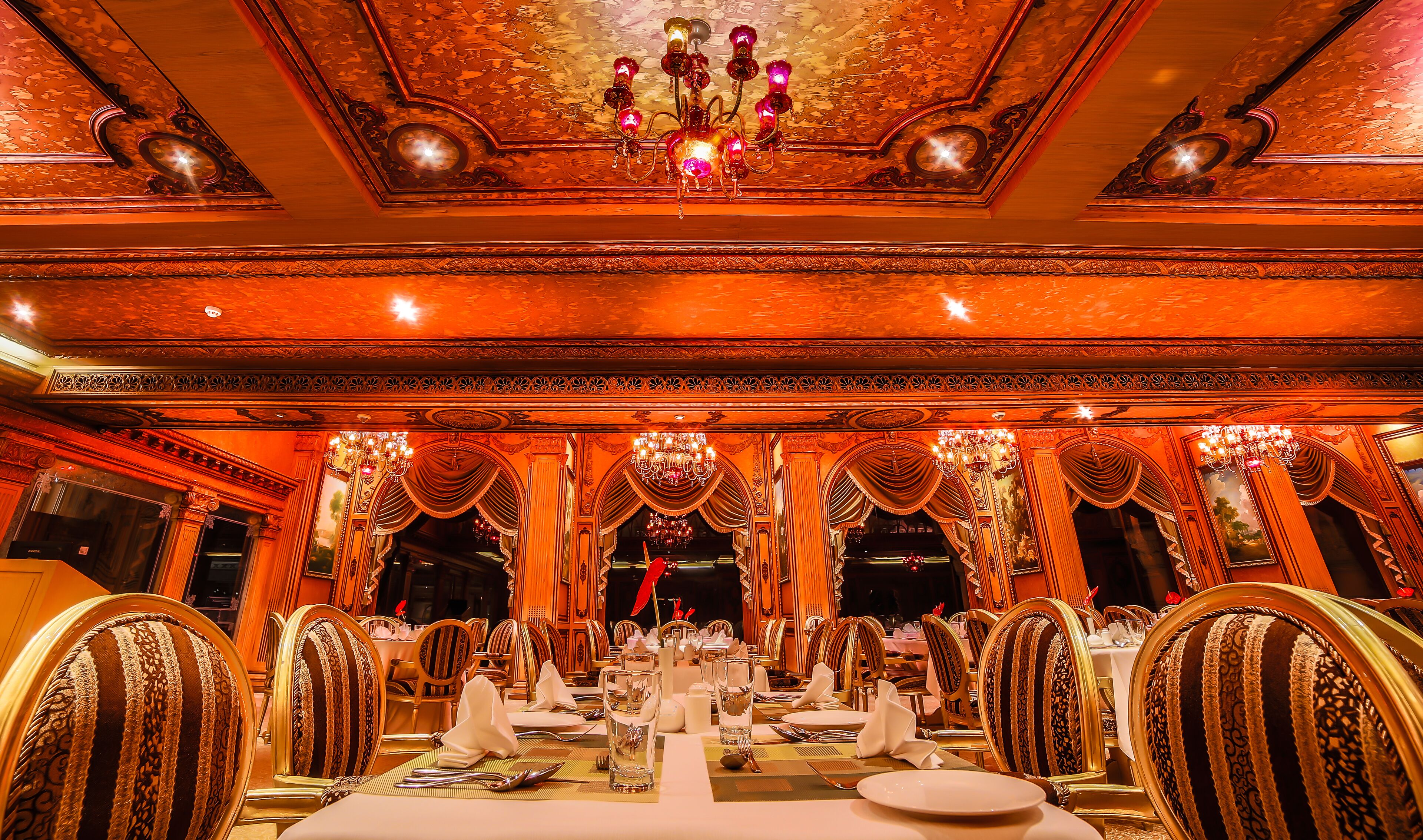 A lavishly decorated banquet hall with ornate chandeliers, high ceilings, and elegant table settings.
