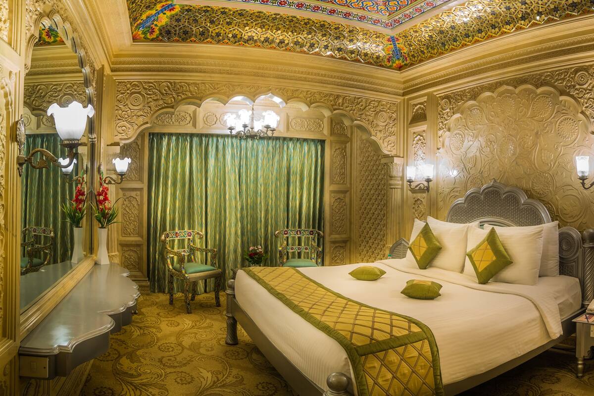 A luxurious room with a large bed, ornate wall decorations, and a chandelier.