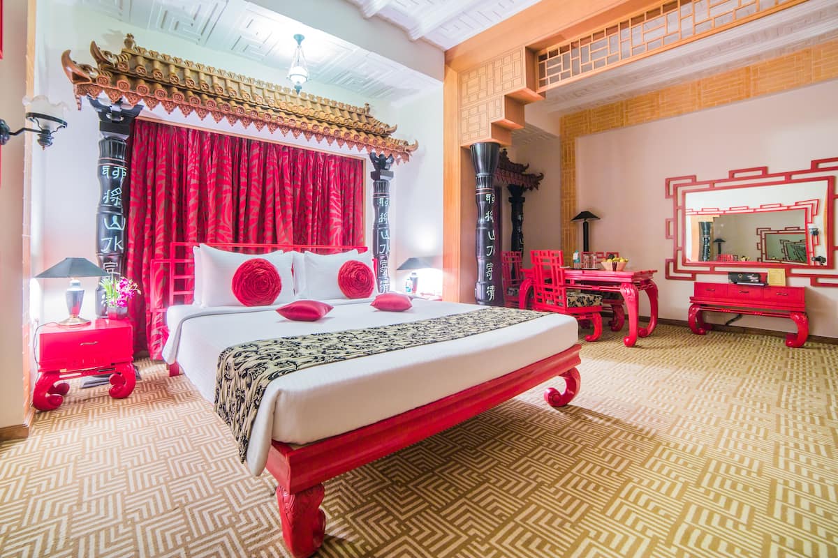 A traditional Chinese-style bedroom with a bed, red curtains, and a red and black patterned bedspread.