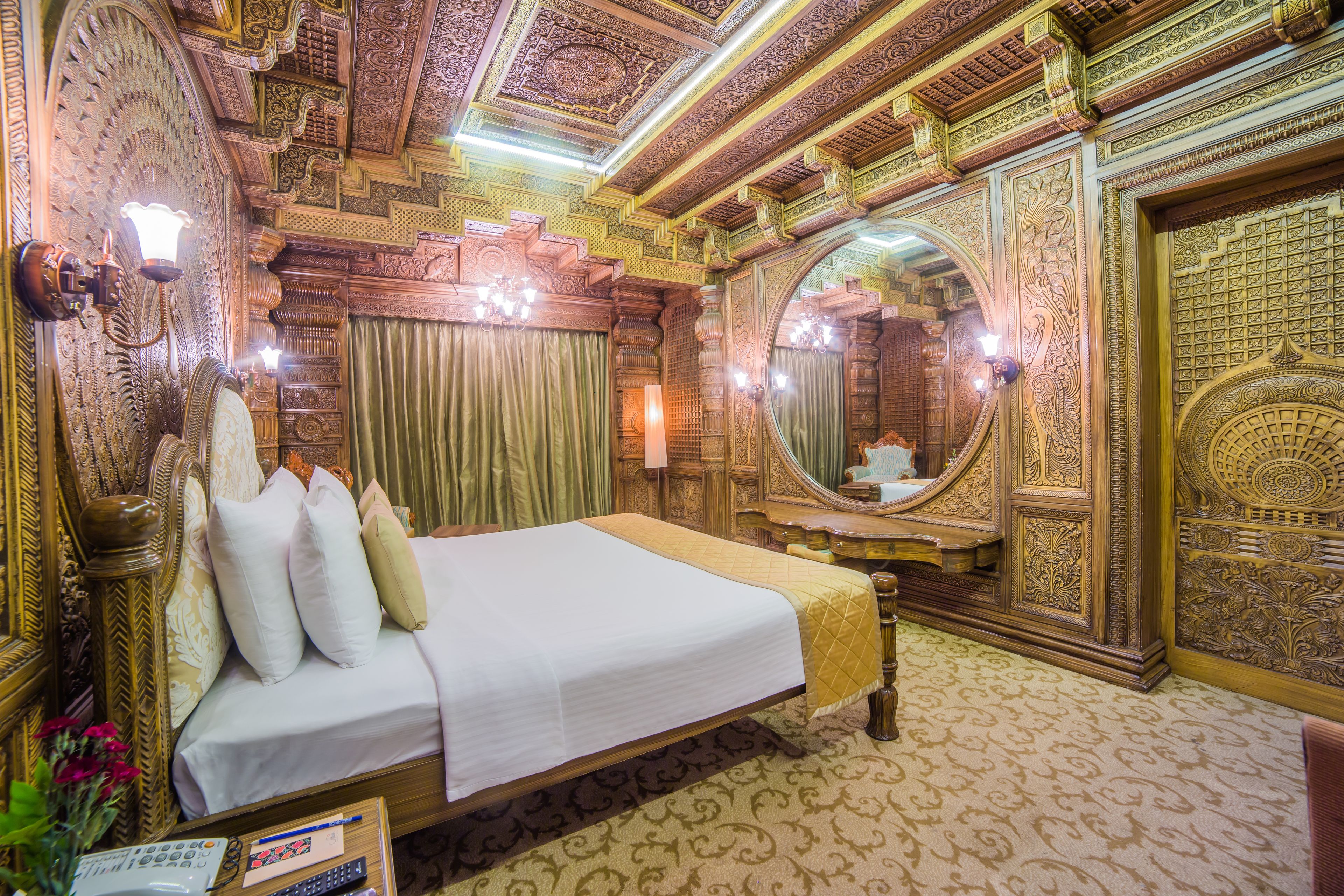 A luxurious room with a large bed, ornate ceiling, and a large mirror.