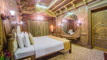 A luxurious room with a large bed, ornate ceiling, and a large mirror.