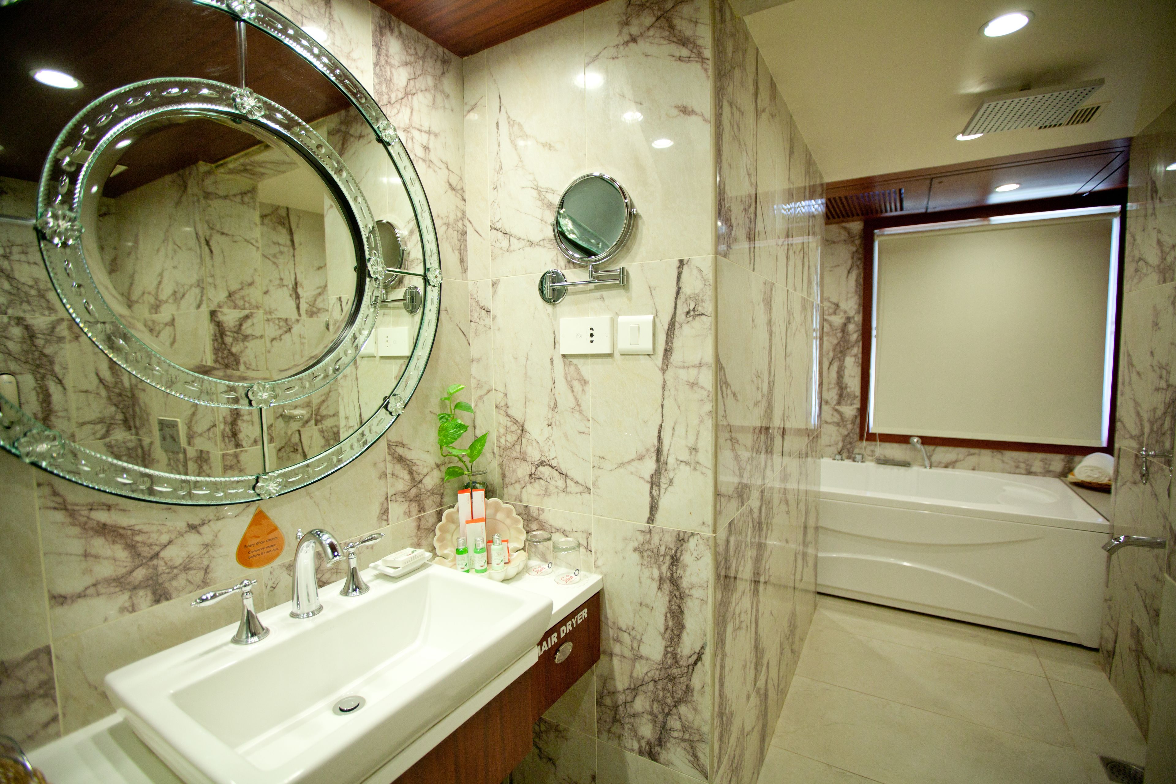 A bathroom with a marble sink, two mirrors, a bathtub, and a shower.