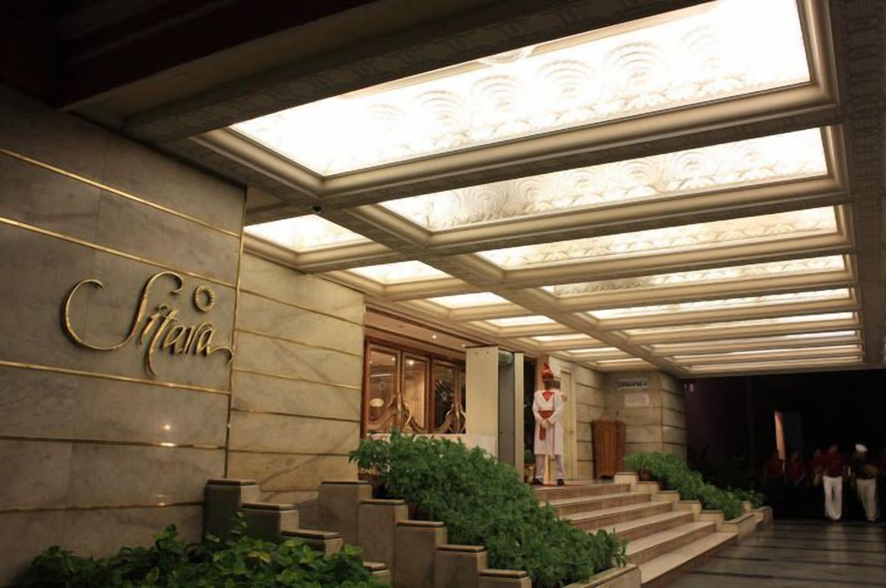 Entrada de un hotel con una imponente escalera, una zona de recepción y un cartel que dice 'Cittanova'.