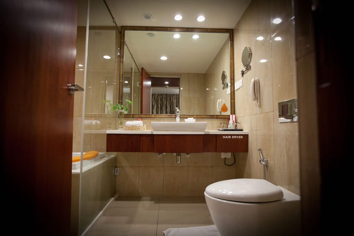 A modern bathroom with a large mirror, a sink, and a toilet.