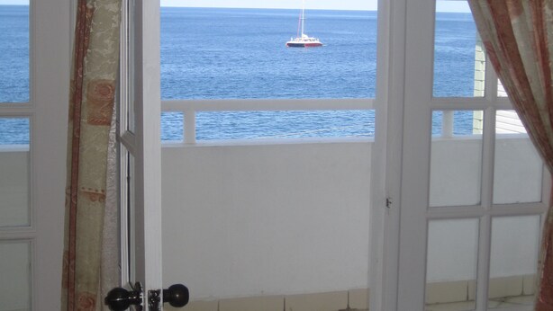 A room with a view of the sea through an open door. - The Downtown Hotel (Soufrière)