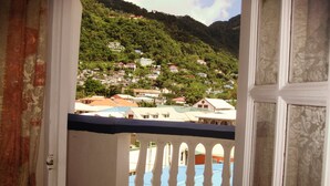 A balcony with a view of a hillside with houses. - The Downtown Hotel (Soufrière)