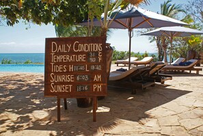 A wooden sign with daily conditions, temperature, tides, and sunrise/sunset times. - Fumba Beach Lodge (Fumba)