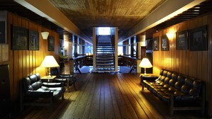 A wooden-floored lobby with leather seating, framed pictures on the walls, and a staircase leading to upper floors. - Hotel de Castro (Castro)