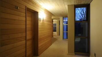 Ein Korridor mit Holzwänden und Teppichboden, der zu einem Raum mit einem großen Fenster führt.