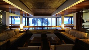 A modern lounge area with a wooden ceiling, large windows offering a view of trees, and a seating arrangement including sofas and tables. - Hotel de Castro (Castro)