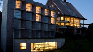 A modern multi-story building with large windows and a sloped roof. - Hotel de Castro (Castro)