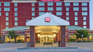 Un hôtel Hilton Garden Inn avec une façade en briques rouges, un logo bien visible au-dessus de l’entrée et une enseigne portant le numéro 2400.