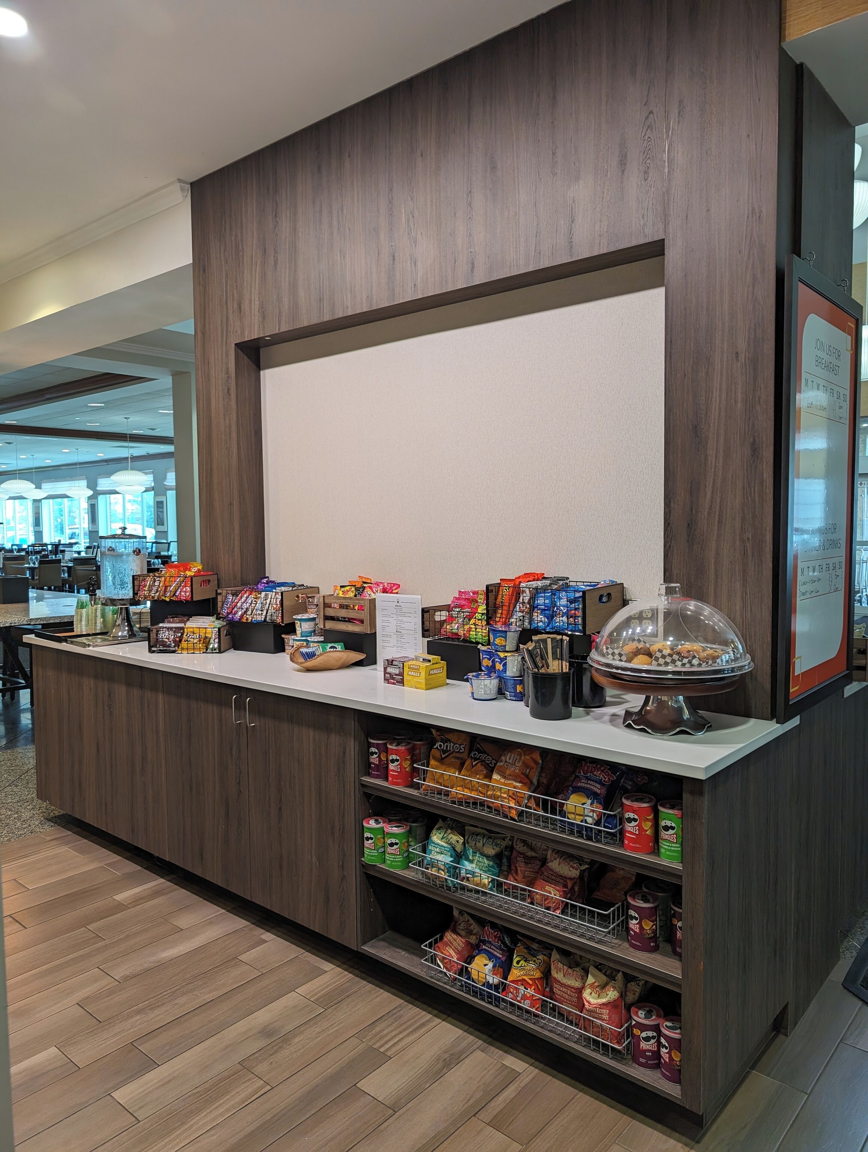 Una barra de desayuno con aperitivos y bebidas, paneles de madera y un cartel con el menú.