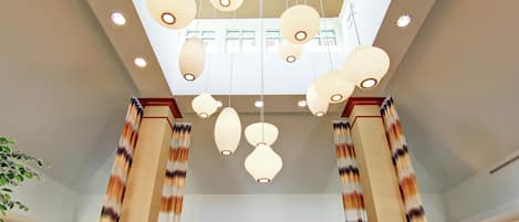 A hotel lobby with a high ceiling, multiple hanging paper lanterns, and wooden columns.