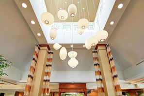 A hotel lobby with a high ceiling, multiple hanging paper lanterns, and wooden columns. - Hilton Garden Inn Ottawa Airport (Ottawa)