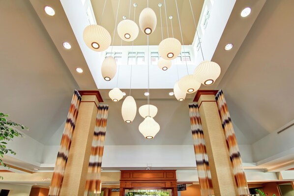 A hotel lobby with a high ceiling, multiple hanging paper lanterns, and wooden columns.