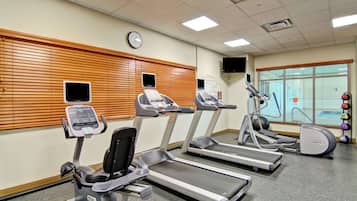 Un gimnasio con cintas de correr, elíptica y bicicleta estática.