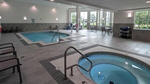 Une grande piscine intérieure, d’une profondeur de 1,20 mètre, entourée d’espaces aménagés avec des sièges et dotée d’un sol carrelé.