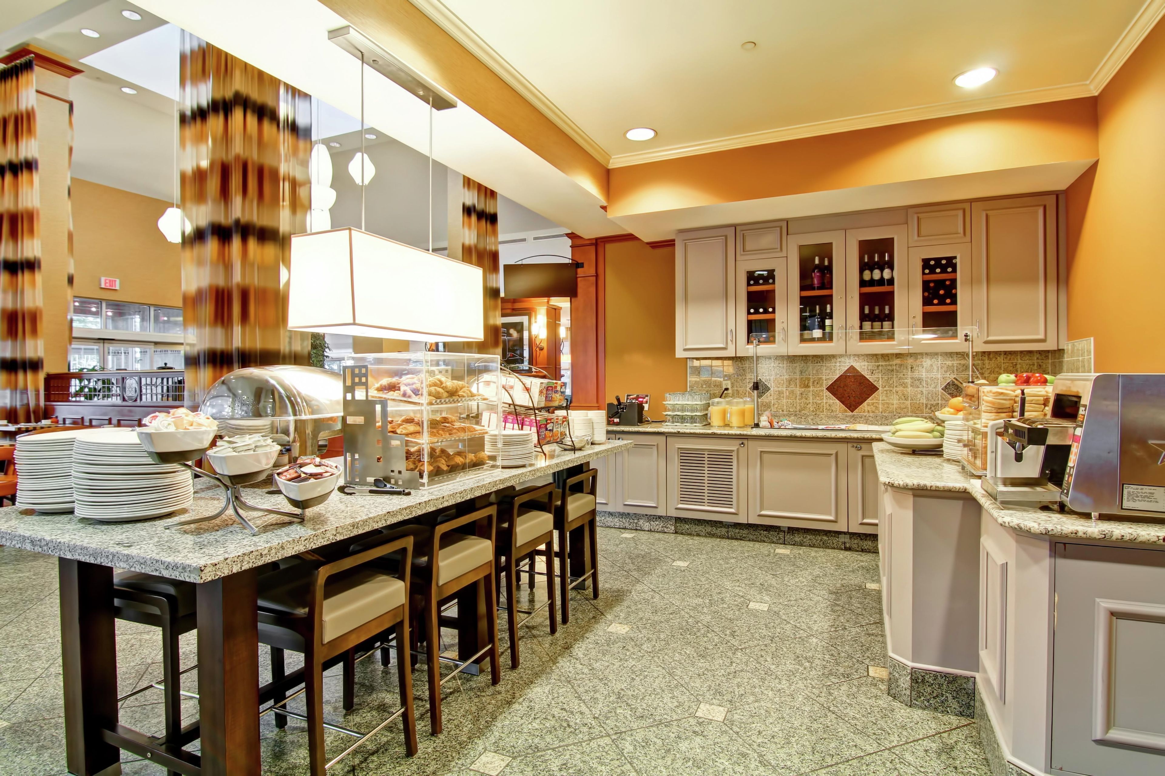 A hotel breakfast area with a buffet setup, including a coffee machine and a variety of food items.