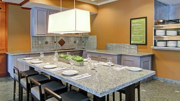Una cocina moderna con encimeras de granito, una isla central con asientos tipo barra y un menú de desayuno en la pared.