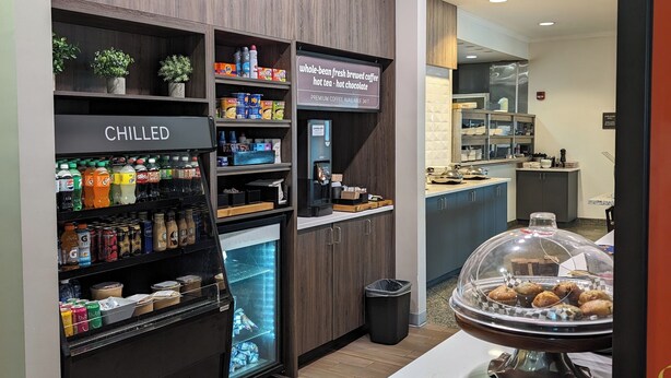 Un café doté d’une vitrine réfrigérée portant l’inscription « PRODUITS FRAIS » et d’un panneau indiquant : « café fraîchement moulu à partir de grains entiers, thé chaud et chocolat chaud ».