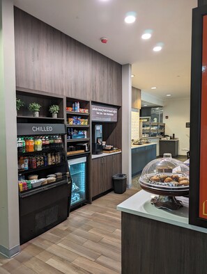 Un café doté d’une vitrine réfrigérée portant l’inscription « PRODUITS FRAIS » et d’un panneau indiquant : « café fraîchement moulu à partir de grains entiers, thé chaud et chocolat chaud ».