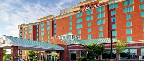 Un Hilton Garden Inn con fachada de ladrillo, varias ventanas y una entrada cubierta.