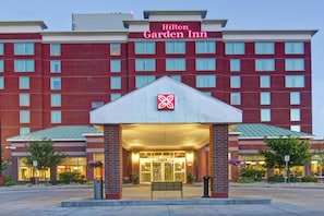 A Hilton Garden Inn with a prominent red-brick facade, a large entrance canopy, and a visible address sign.