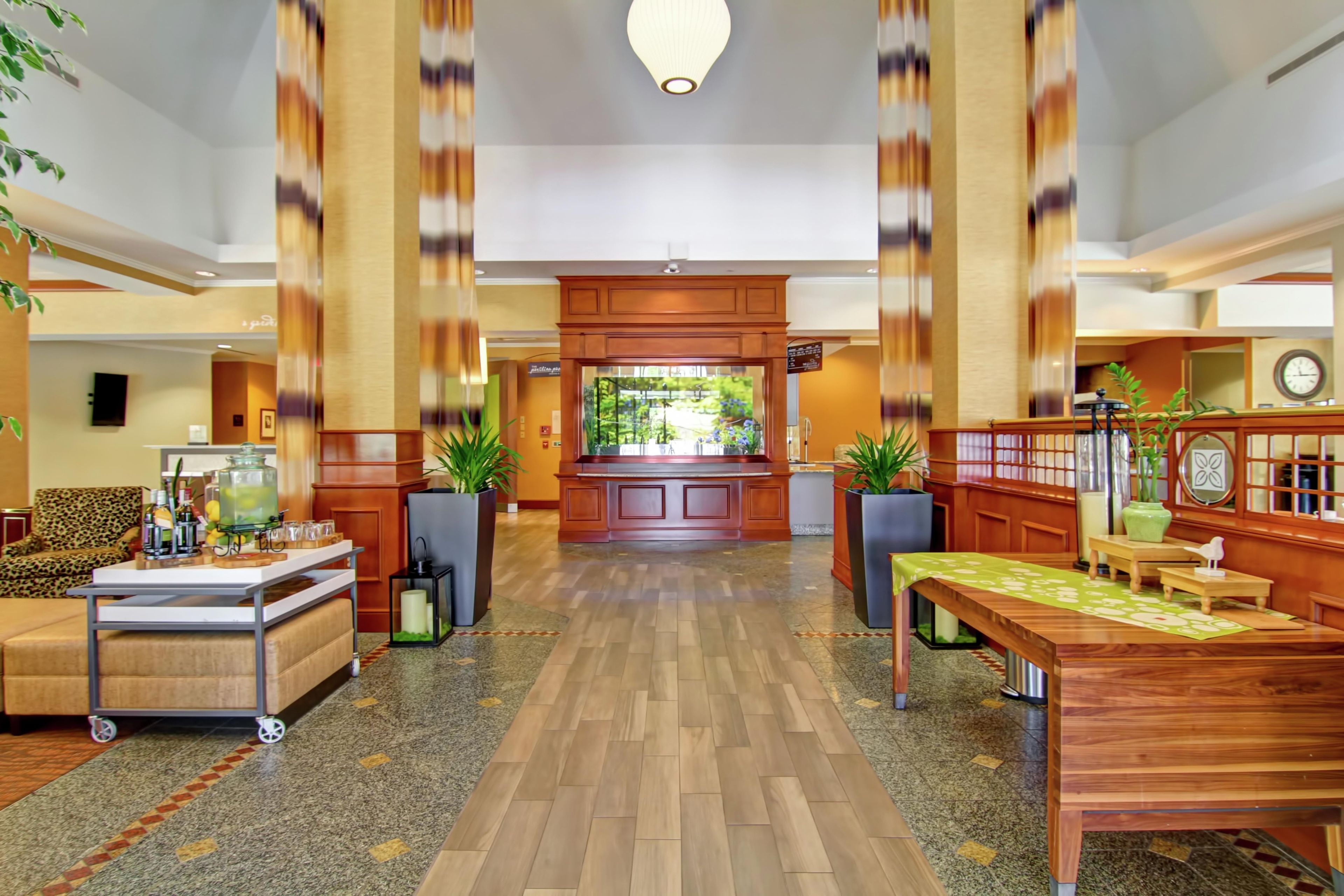 Een hotel lobby met een receptiebalie, een zithoek en uitzicht op de omgeving.