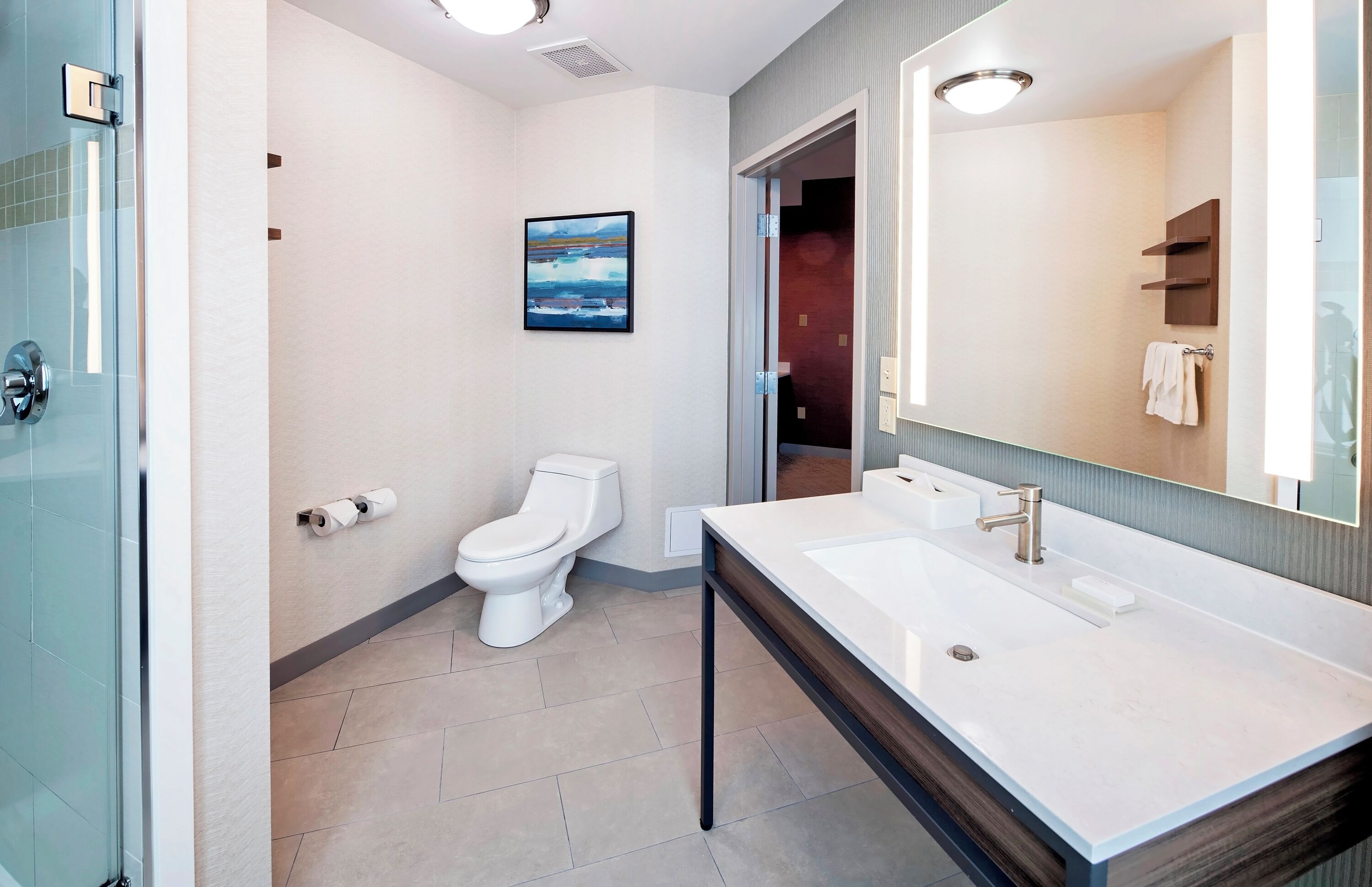 Une salle de bain moderne avec un lavabo blanc, un grand miroir et des toilettes.