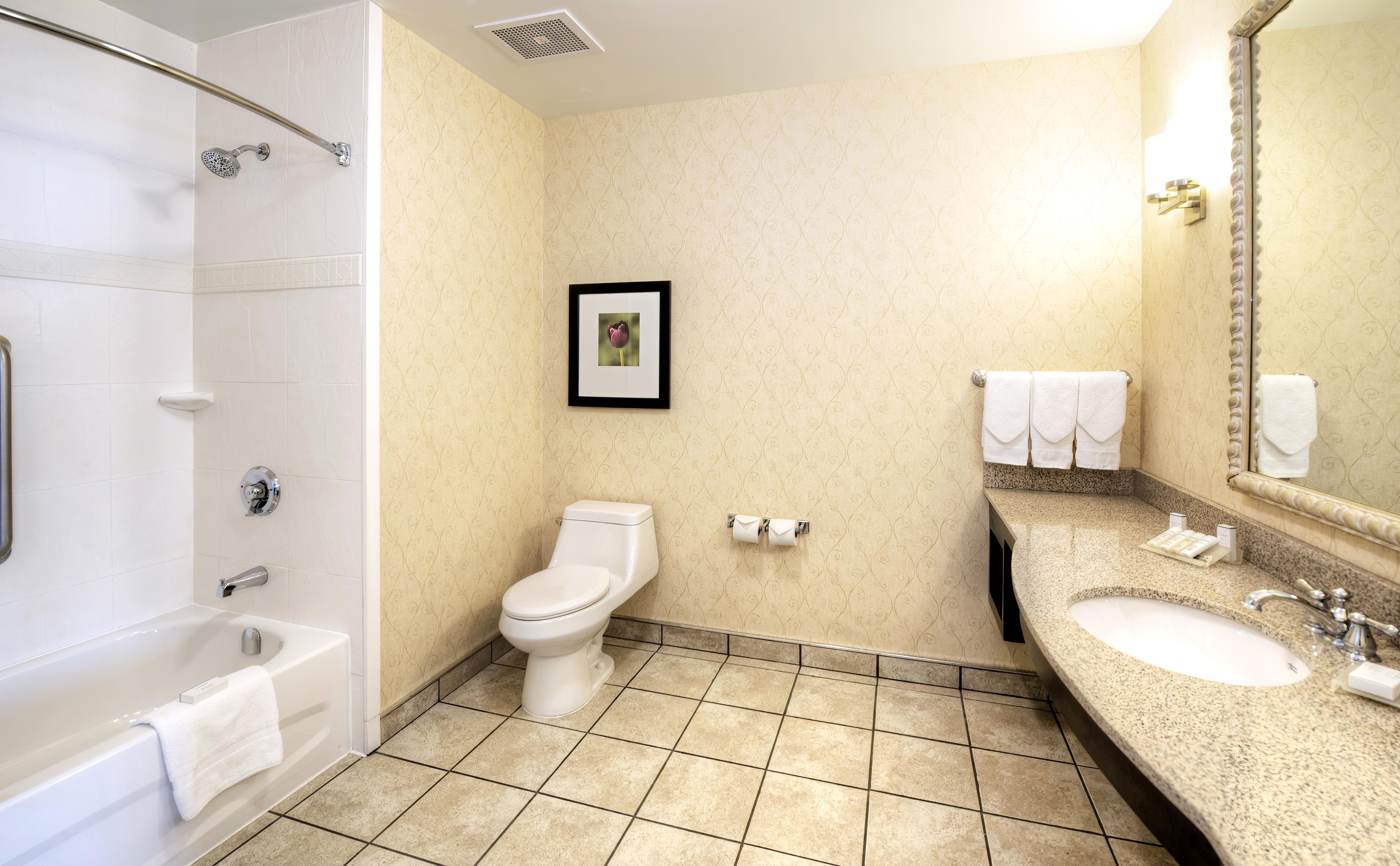 Ein Hotelbad mit Badewanne, Toilette, Waschbecken und Duschbereich.