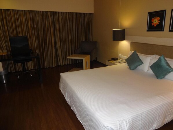 Una habitación de hotel con una cama grande, un escritorio con silla, un teléfono y una lámpara.