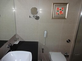 A bathroom with a white sink, a toilet, a mirror, and a telephone.