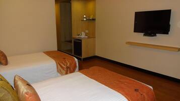 A hotel room with two beds, a TV, a small desk, and a mirror.