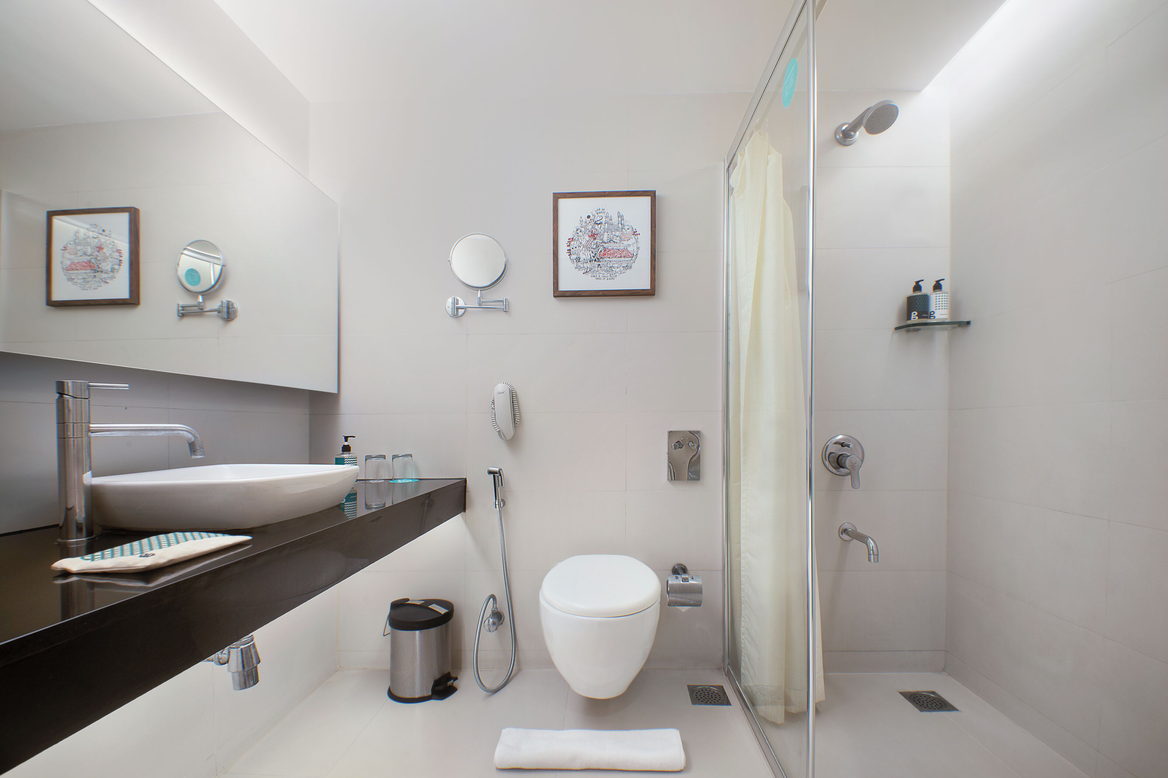 Un baño moderno con un espejo grande, un lavamanos, inodoro y zona de ducha.