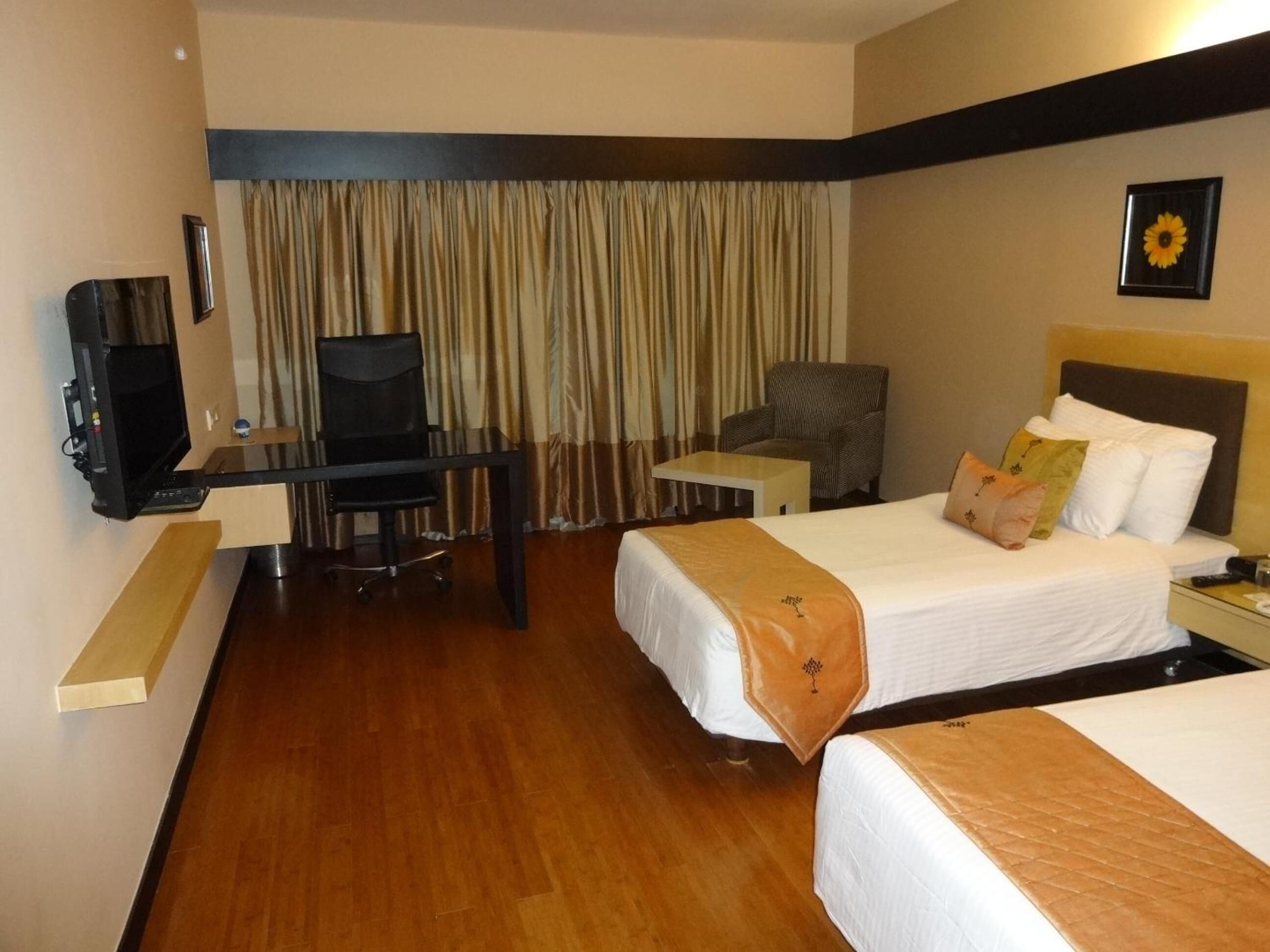 A hotel room with two beds, a desk with a computer, a chair, and a small table.