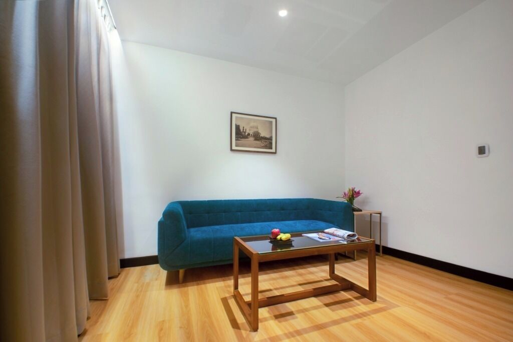 A room with a blue sofa, a wooden coffee table with a magazine and fruit, and a framed picture on the wall.