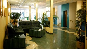 A lobby with a checkered floor, black leather sofas, and potted plants. - Hotel Bara Junior (Budapest)