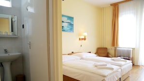 A hotel room with a bed, a chair, a lamp, and a painting on the wall. - Hotel Bara Junior (Budapest)