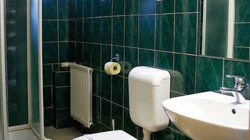 A bathroom with a toilet, sink, and green marble walls.