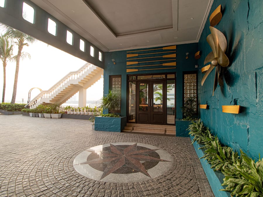 L’entrée d’un hôtel se caractérise par un motif de sol en forme d’étoile, un escalier et un mur décoratif orné d’un motif en éventail.